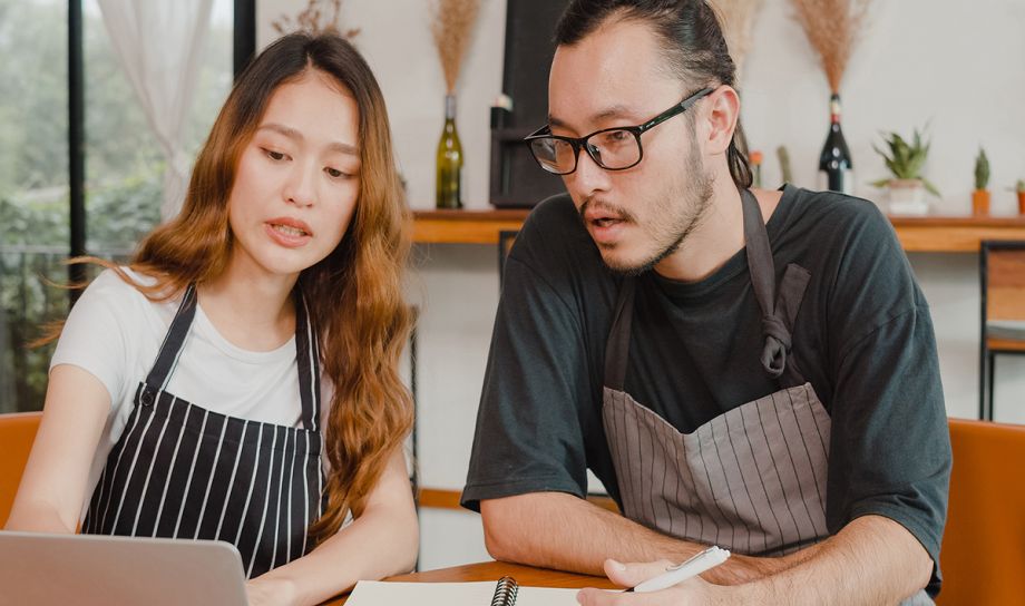 Small business owners sitting down and discussing AI on a laptop